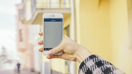 Sarı bir binanın önünde tutulan akıllı telefon